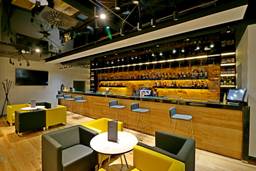 Moderne Hotellobby mit Bar, gelben Sesseln und geometrischem Teppich